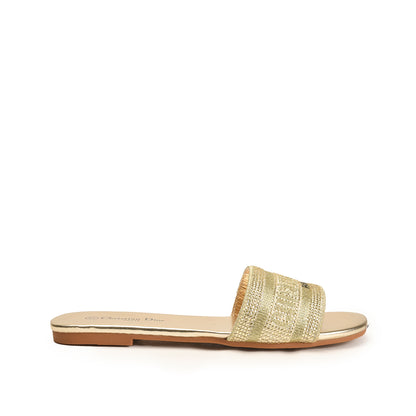 A pair of beige flat shoes with a decorative metallic bar on the vamp and a flat sole.