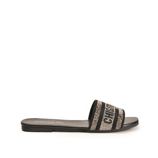 A pair of women's slippers with a metallic embellished strap and a flat sole.