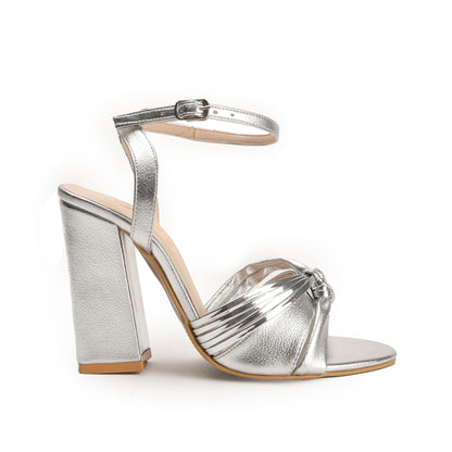 A silver-colored sandal with a block heel and an open-toe strap.
