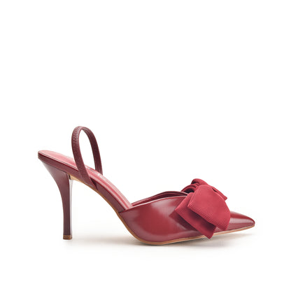 A red, suede court shoe with a pencil heel and a decorative bow on the toe.