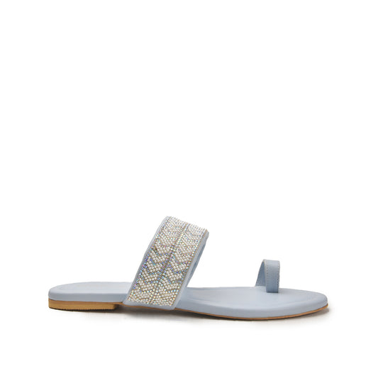 A blue slip-on slipper with a decorative metallic pattern on the sole.