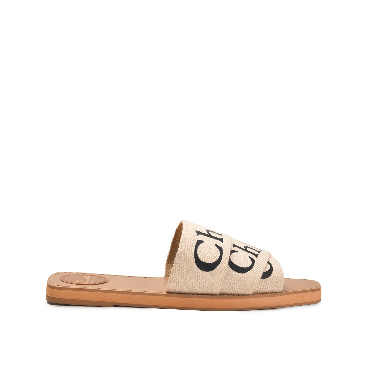 A pair of beige flat sandals with a text pattern on the strap and a simple sole design.