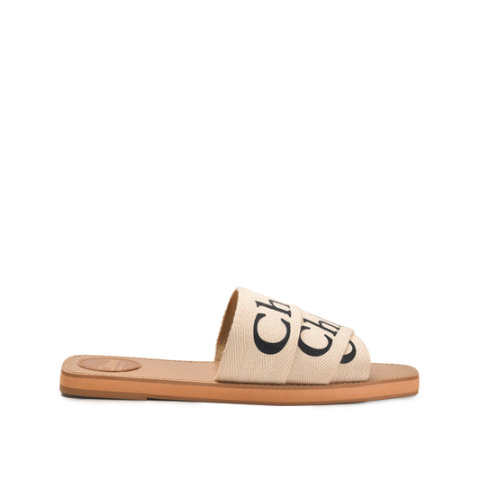 A pair of beige flat sandals with a text pattern on the strap and a simple sole design.